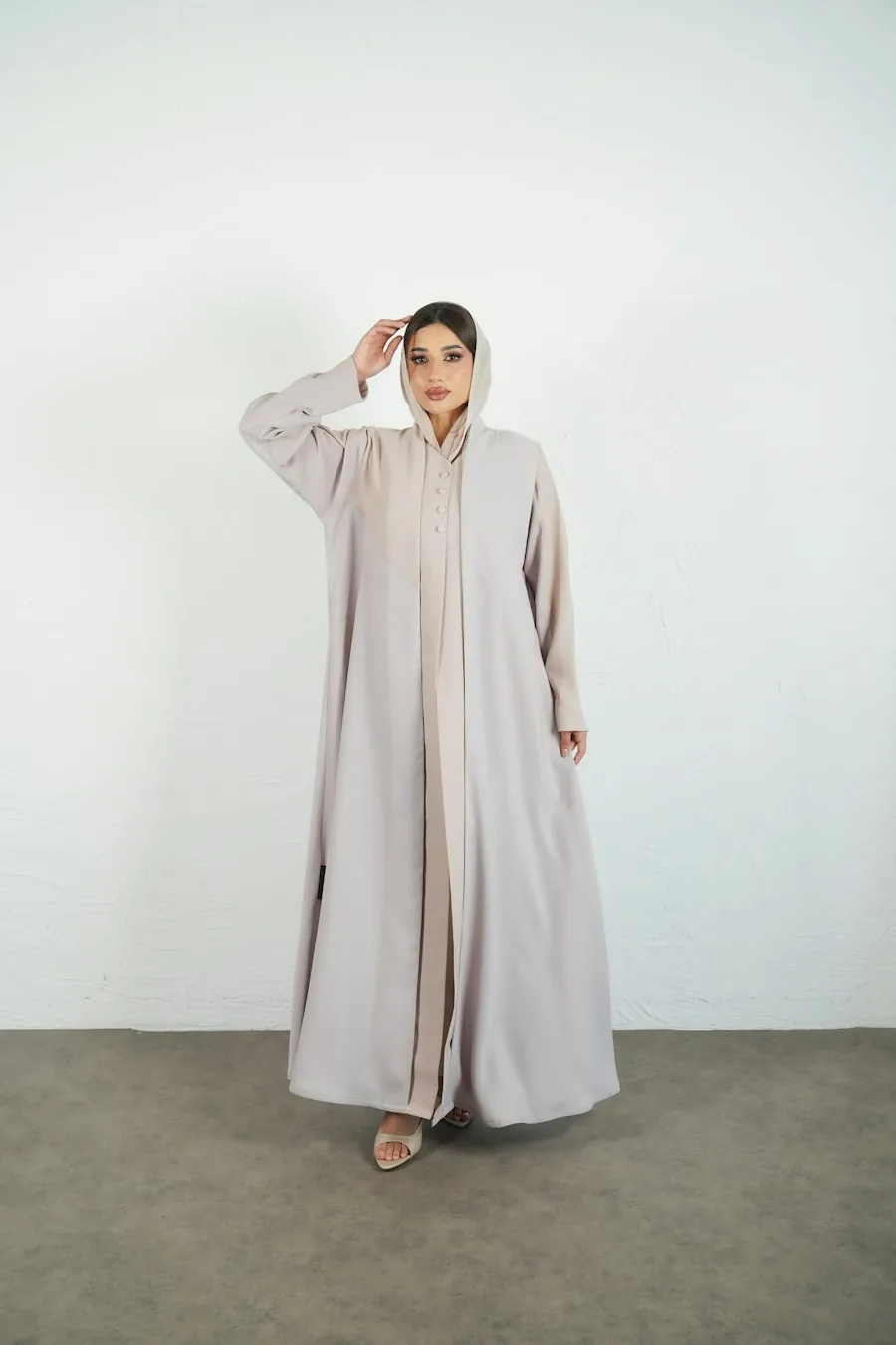 Long ivory modest fashion look against a pale wall